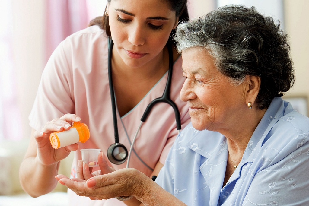 Hispanic nurse helping senior woman with medication